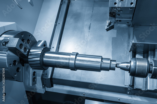 High-precision finishing process of a metal component on a CNC lathe machine utilizing a tailstock for rigid support in a light blue scene.