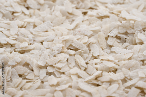 closeup of raw white flattened rice flakes, known as poha. A staple Indian breakfast ingredient, these dry organic cereal flakes background texture
