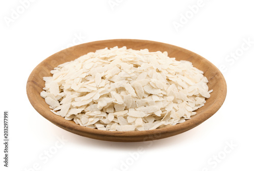 closeup of raw white flattened rice flakes, known as poha. A staple Indian breakfast ingredient, these dry organic cereal flakes isolated on white background in wood blow
