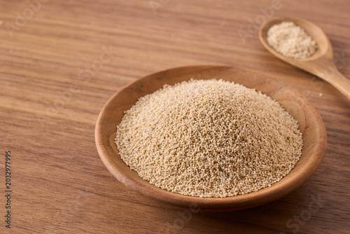 closeup raw white poppy seeds, known as khus khus, served in a wooden bowl on a timber table. This organic spice is a key ingredient in Indian cuisine, perfect for healthy cooking and food background