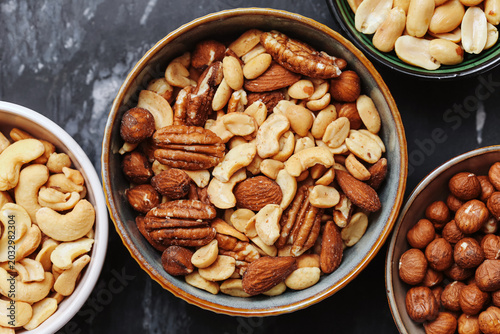 Foto Mixed nuts in ceramic bowls on dark background