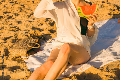Obraz na płótnie Enjoying watermelon and drinks on the beach during a sunny day with friends while sitting on a blanket