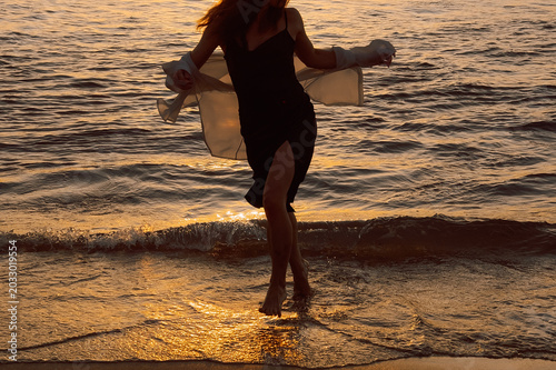 Fotografie Silhouette  person with arms outstretched at beach during sunset near ocean waves