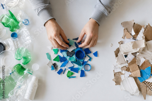 Hands organizing colorful recycled materials for art project