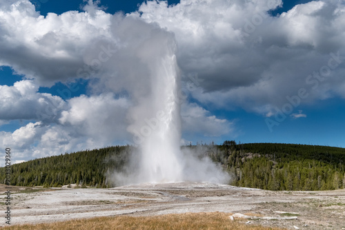 Photos Grand Geyser Eruption Under Blue Sky with Fluffy White Clouds