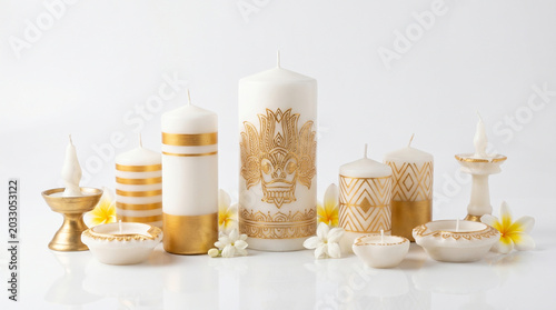 Elegant white and gold decorative candles with tropical flowers isolated on white background