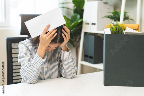 Bild auf Leinwand Unemployment, quitting job, desperate asian young business woman holding a resignation letter, resigning from company packing belongings, stuff in box, layoff or leaving, changing work employment