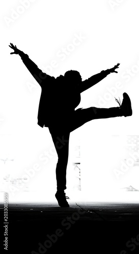 Silhouette of dancer in dynamic pose against bright background