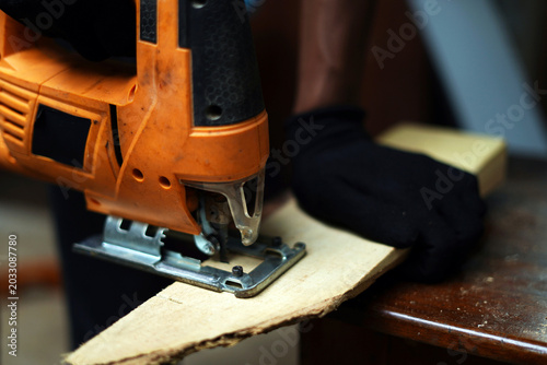 Carpenter cutting wood with electric saw. closeup image