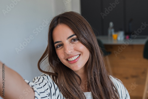 Foto Happy young adult woman with long brunette hair smiling at camera while taking a