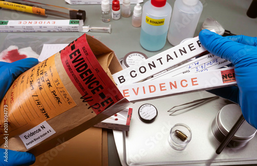 Police scientist takes evidence swab bag boxes to analyse for traces of dna from homicide in crime lab, concept image