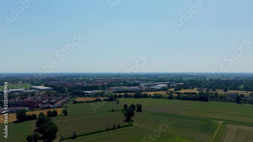 Rural Landscape Panorama: An expansive aerial view showcases a verdant rural landscape under a clear blue sky, featuring patchwork fields, scattered trees, and a distant town.