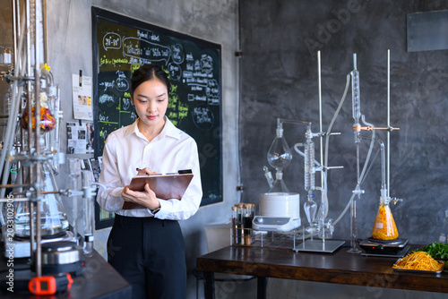 Konstfotografi Young Asian Female Scientist Writing on Clipboard in Food Science Laboratory wit