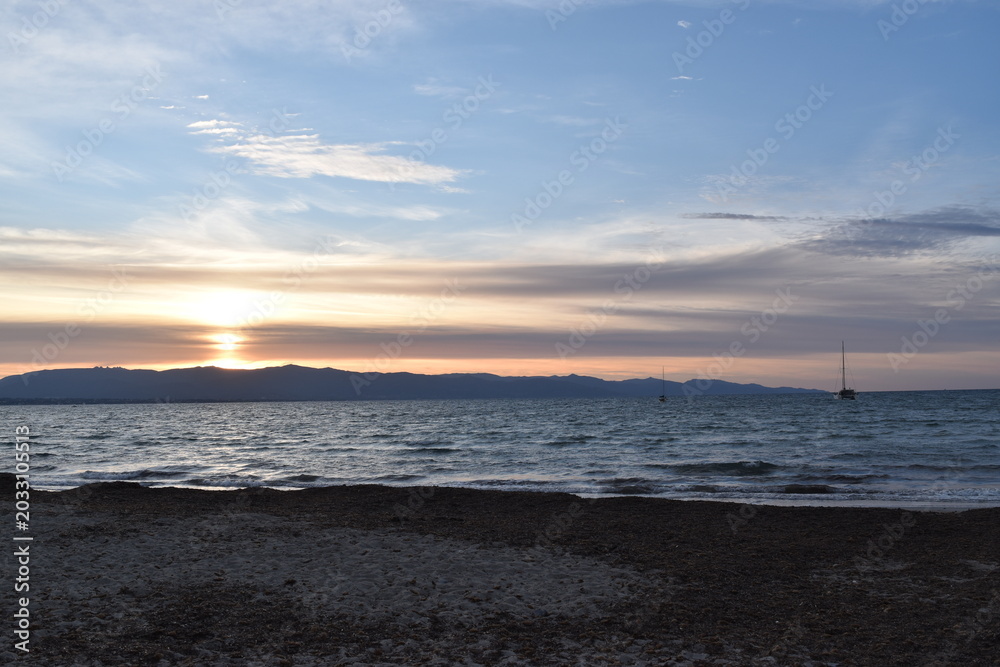 Obraz premium sunset over the sea with sailboats and mountain silhouette Poetto