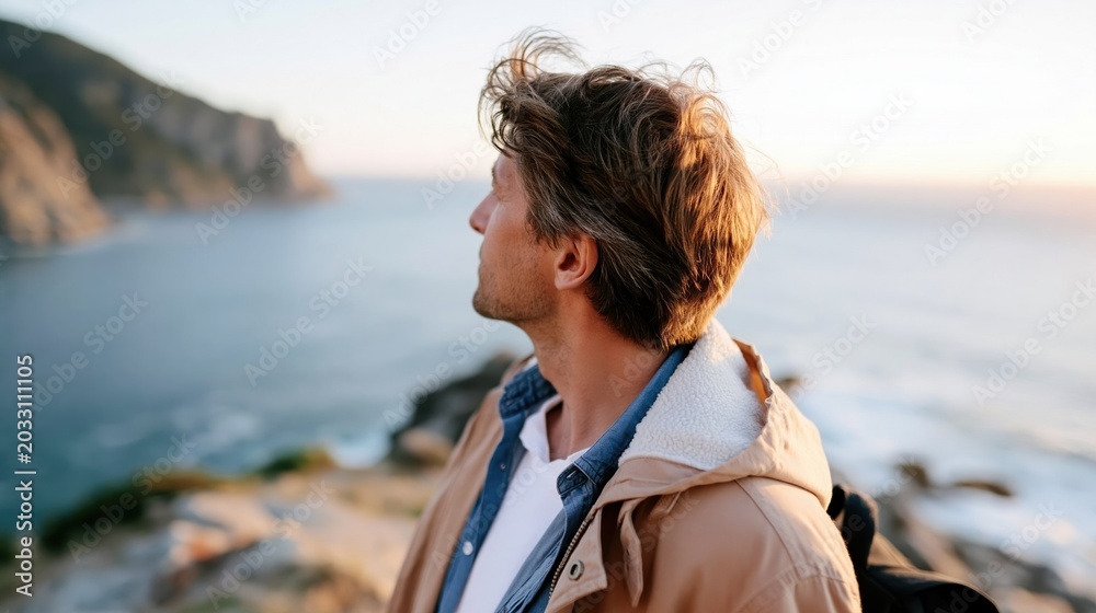 Fototapeta premium A reflective man gazes at a stunning coastal sunset, capturing a moment of serenity and introspection amidst the beauty of nature's vibrant colors.