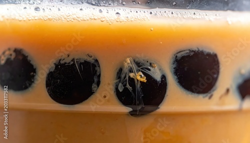 Close Up Black Tapioca Pearls Floating in Orange Bubble Tea Cup