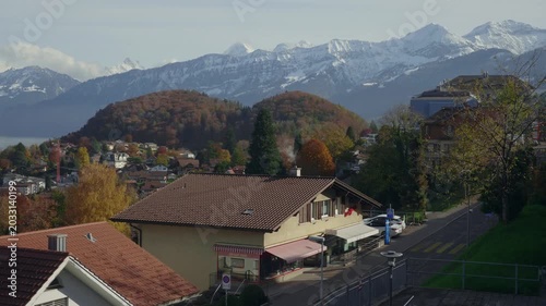 A picturesque view of a quaint village nestled in the valley, surrounded by majestic mountains and vibrant autumn foliage. The tranquil setting showcases the beauty of nature and architecture, invitin