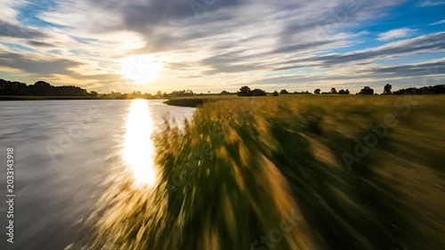 Golden Sunset Over Calm River and Lush Green Field.