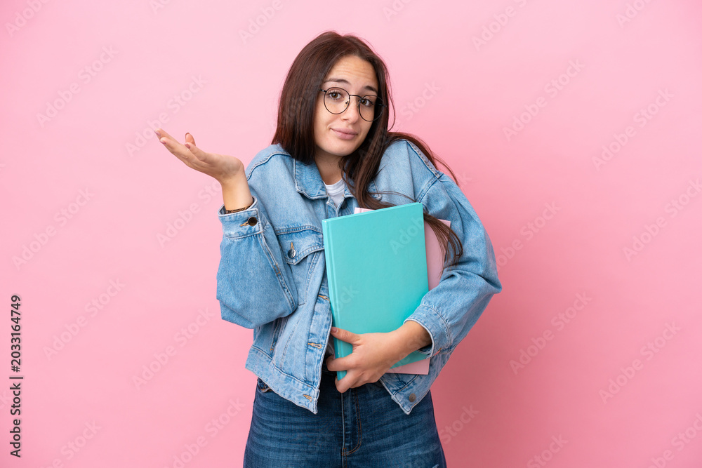 Fototapeta premium Young Ukrainian student woman isolated on pink background having doubts while raising hands