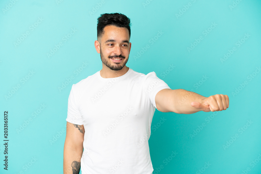 Fototapeta premium Young caucasian man isolated on blue background giving a thumbs up gesture