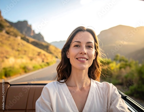Smiling Young Woman Sitting in Convertible Car on Scenic Mountain Road at Sunset