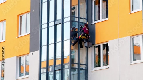 Exterior cleaning operation. Urban highrise building cleaning performed using specialized rope access and safety equipment