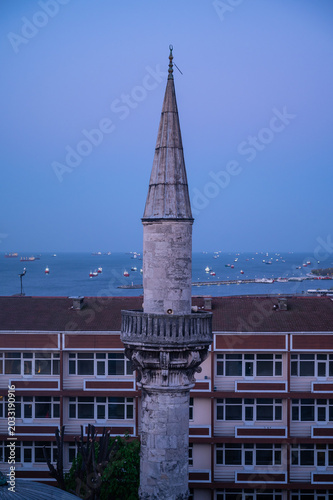 mosque minaret with a background of the sea and cargo ships
