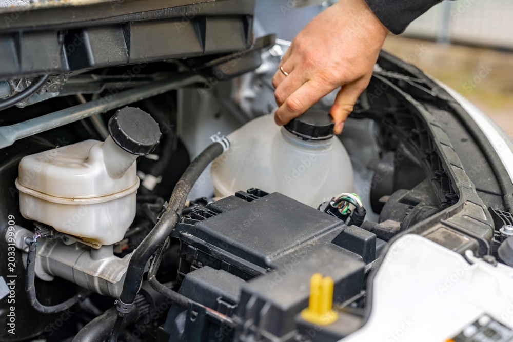 Obraz premium Refilling coolant to prevent engine overheating. Adding fluid to radiator for system safety. Engine cooling system is replenished with fluid to prevent overheating and maintain performance