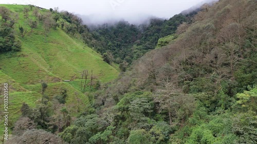 Drone reveal shot of lush green mountains in Coronado, Costa Rica with low clouds and mist