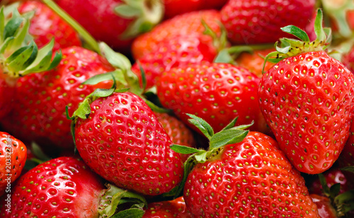 Close up background texture of fresh organic red strawberries with green leaves