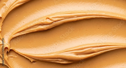 A close-up shot of creamy light brown peanut butter spread smoothly across a surface with soft ripples and a rich velvety sheen texture, delicious, tan, luscious