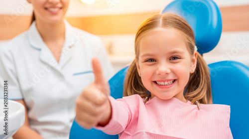 Happy young girl gives thumbs up after successful dental check-up with dentist