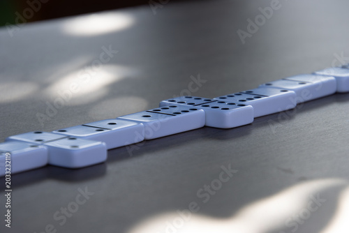 Single row of dominoes on dark tabletop