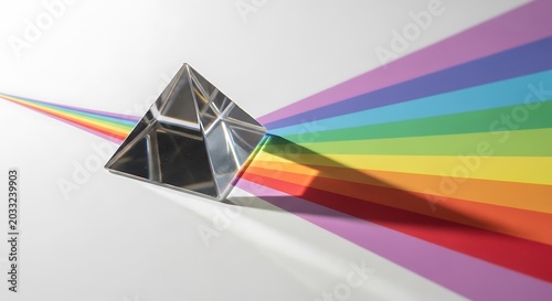 Glass prism refracting light into a rainbow spectrum, isolated on white background