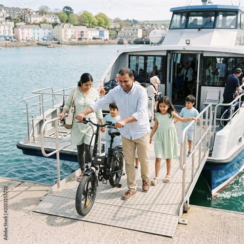 Happy South Asian family with children and an electric bike disembarking from a ferry at a coastal harbor
