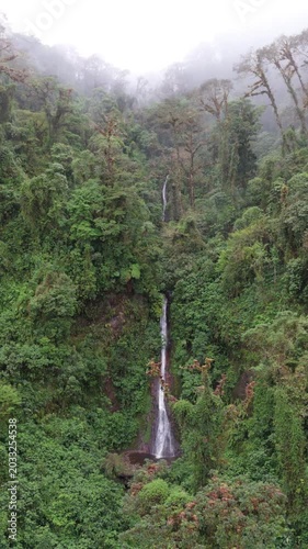 Drone flying backward, pulling back from a cascading waterfall in the cloud forest of Coronado, Costa Rica