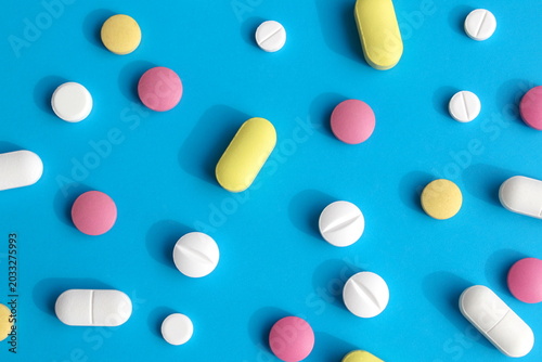 Texture of multi-colored pills lying on a blue background.	
