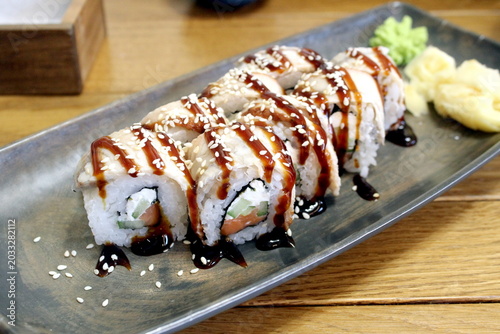 There is a long plate with Japanese rolls on the table.