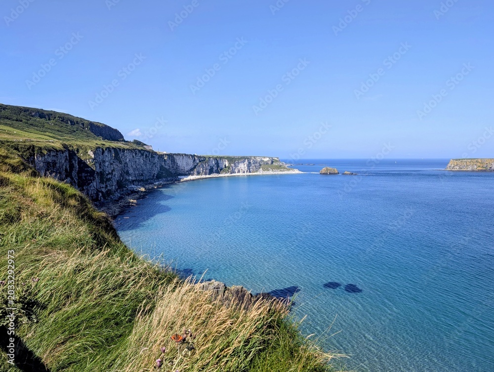 Obraz premium Breathtaking panoramic view of the curved coastline, dramatic white cliffs and turquoise sea from Carrick-a-Rede cliff edge, Northern Ireland.