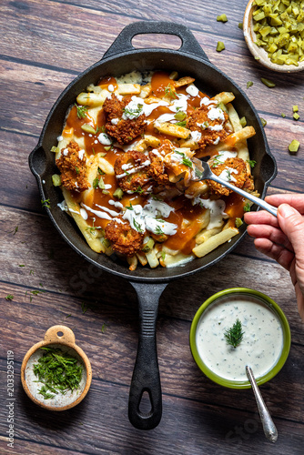 Top down view of a skillet filled with deep fried dill pickle poutine.