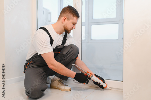Canvastavla Worker applying caulk sealant during window renovation process