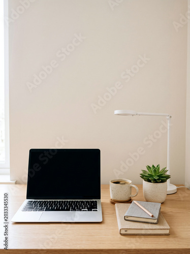Laptop with blank screen on wooden desk with coffee and plant