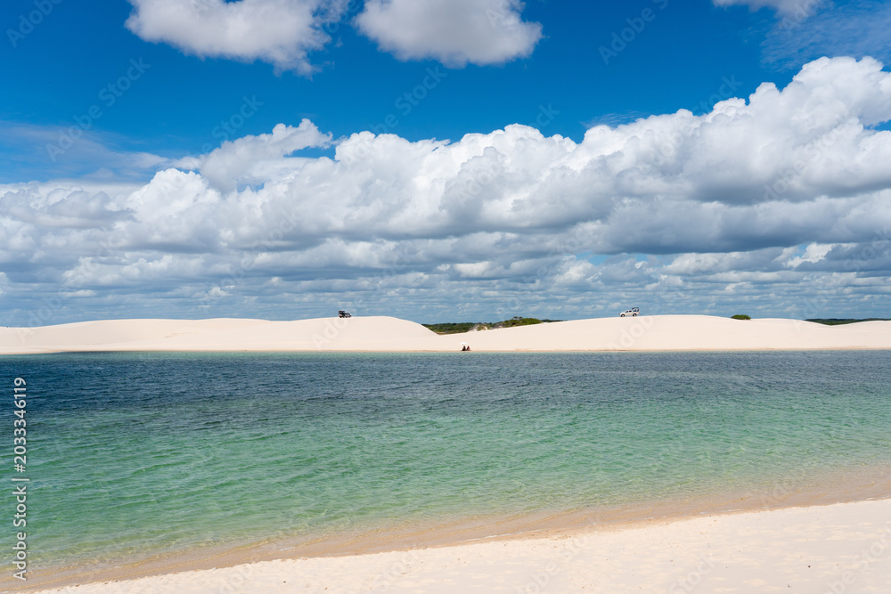 Fototapeta premium Paisagem dos Lençóis Maranhenses, no Maranhão, com lagoas naturais de água cristalina, dunas brancas, céu azul e formações de areia em um dos cenários mais conhecidos do nordeste do Brasil.
