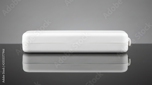 Closed white plastic thermometer storage case lying on reflective surface, medical equipment, healthcare supply, clinical tool