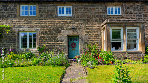 Traditional stone cottage facade with beautiful green garden in Hathersage