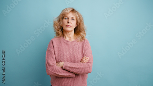 Konstfotografi Mature woman standing with arms crossed, expressing skepticism and disapproval,