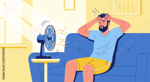 Man sweating and struggling with heat, sitting in front of a fan at home