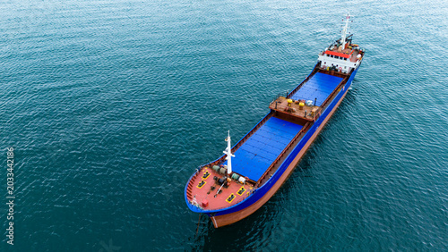Aerial perspective of large blue and red bulk carrier ship sailing on deep ocean water