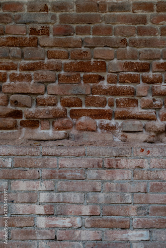 Muro antiguo de ladrillo rojo con diferentes tonos y texturas.
