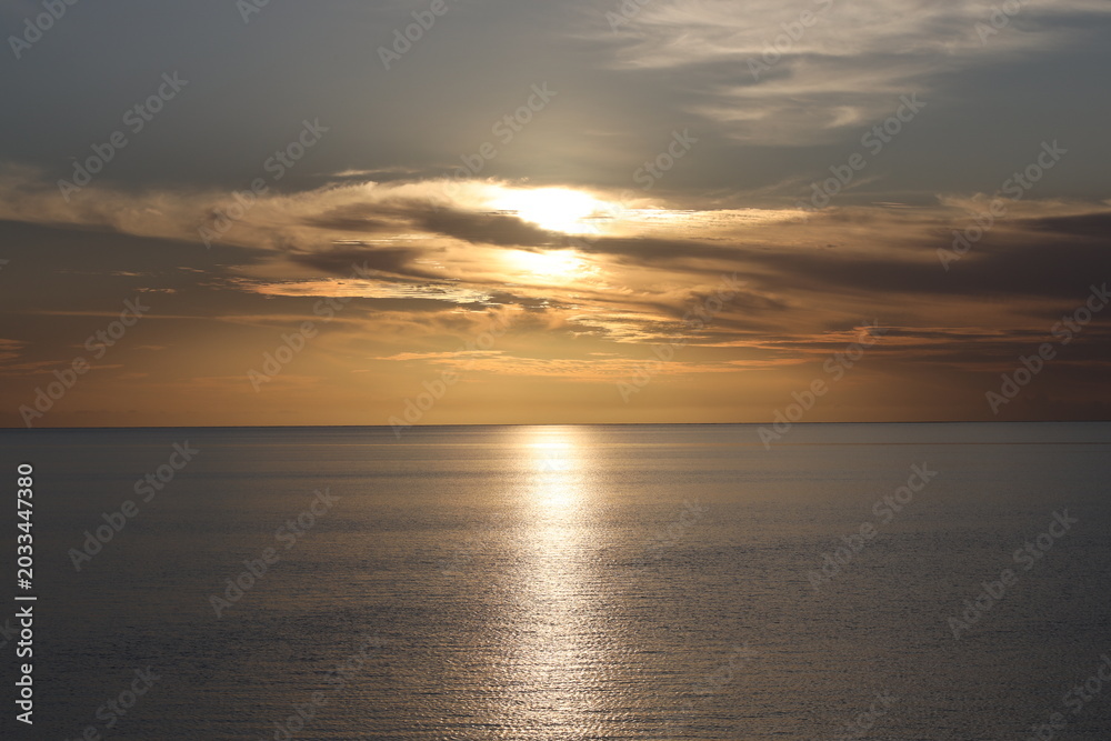 Obraz premium clouds blaze in orange, copper, gold, blinding white above calm seas as sunset nears (close-up, landscape, tropical) 3684